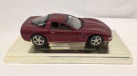 Left side view of maroon Corvette model on display base