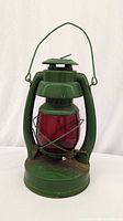 Full view of green lantern with red globe and handle