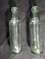 Pair of clear green glass bottles standing upright