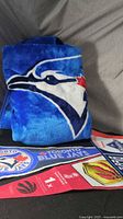 Rolled fleece blanket showing Blue Jays logo with pennants below