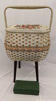 Front view of wicker sewing basket on legs with Singer case