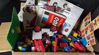 Open box showing assorted vintage LEGO pieces, baseplate and manuals