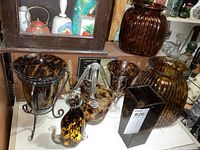 Group shot of seven brown mottled art glass pieces on shelf