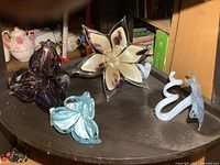 Group of four art glass flower sculptures on shelf