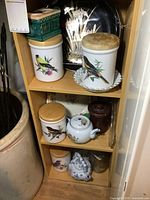 Full view of cabinet shelf contents including canisters, charger, trinket box, and items on lower shelves