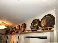 Row of nine framed collector plates displayed on shelf