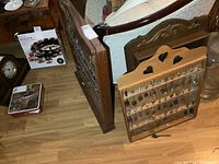 Three wooden spoon racks standing on floor next to furniture, racks filled with souvenir spoons