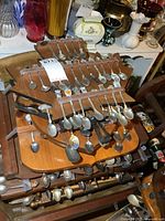 Multiple racks stacked showing numerous souvenir spoons