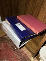 Two binders and hardcover book stacked