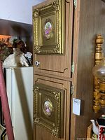 Full view of two gilt framed porcelain tiles mounted vertically