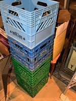 Stack of four plastic milk crates two blue one dark blue one green