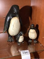 All three carved wood penguin figurines on shelf