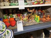 Wide shot of lower shelf showing multiple novelty salt and pepper shakers and glass salters