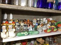 Wide view of upper shelf showing majority of salt and pepper shaker pairs