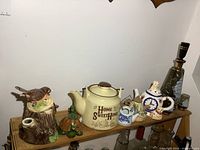 Shelf showing multiple teapots, decanter, cups