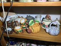 Shelf showing multiple novelty and traditional teapots and cups