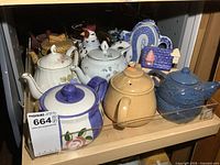 Shelf showing nine assorted teapots
