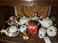 Shelf containing all ten ceramic teapots in assorted novelty and floral designs