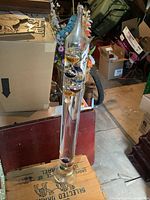 Full view of glass Galileo thermometer standing on wood crate