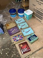 Group shot of all tins on floor including plastic tubs and powder tin