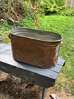 oblique view of copper boiler on bench showing patina and shape