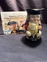 Front view of Jolly Toby jug with brochure behind