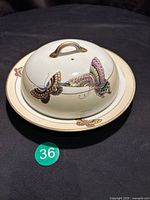 Top view of covered serving dish showing butterfly decoration and underplate