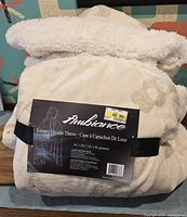 Front view of packaged Ambiance hooded throw showing label and dimensions
