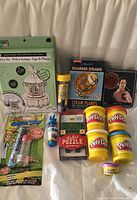 Group shot showing all boxed and packaged items including Play-Doh tubs, kits and puzzle