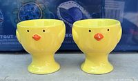 Two yellow ceramic chick egg cups front view