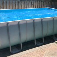 Rectangular above-ground pool with blue bubble cover installed