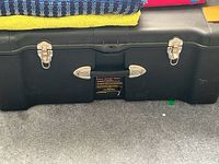 Full front view of large black Contico plastic storage lock box showing double metal latch locks and central handle, minor scuffs visible on surface.