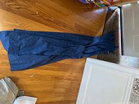 Photo showing full length of blue curtain panels laid flat on wood floor.