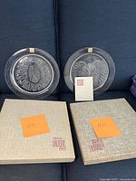 Two Lalique collector crystal plates dated 1970 and 1971 shown with original boxes and certificate.