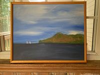 Frontal view of the framed landscape painting showing the full artwork with the hill on the right, sky above, water below, and two small sailboats near the left edge.