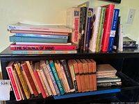 Books arranged on shelves with visible titles including 'The Science of Mind', 'Snoopy', 'Dave Barry's Complete Guide to Guys', and various hardcover and paperback editions of vintage and classic books.