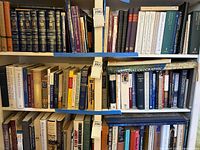 Bookshelves filled with a mixed collection of hardcover and paperback books on Jewish history and religion. Titles visible include 'National Geographic Atlas of the World' and various Jewish historical and religious topics.