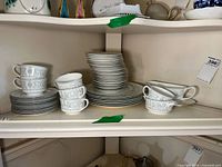 Full view of dinnerware set including stacked plates, cups with saucers and serving bowl