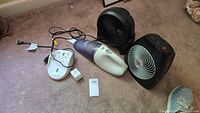 Entire lot showing two fans, one handheld vacuum, charging base, and power cord on carpet.