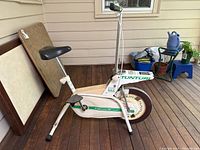 Side view of the white stationary exercise bike showing the padded seat, frame, and front wheel with Tunturi branding.