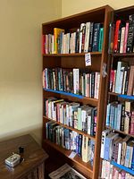 Full frontal view of a medium brown wooden bookcase filled with books on shelves.