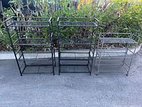 Three folding metal shelving units shown side by side (two black units relevant) displaying overall style and shelf count