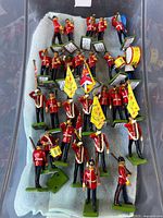 Bin containing painted metal British Guards figures with flags, drums, bugles and music stands