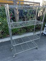 Full view of wire shelving unit showing all four shelves and casters