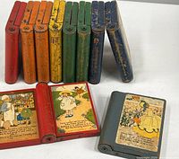 Ten painted wooden storybook blocks arranged to show spines and open block with nursery rhyme illustration and text.