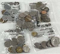 Five clear plastic bags containing foreign coins in various sizes and metals.