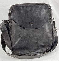 Front view of black leather shoulder bag showing flap closed, strap visible.