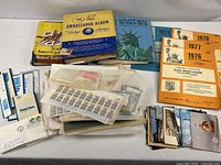 Overview of three hardbound stamp albums, two orange supplement albums, loose stamps in glassine sleeves, postcards and envelopes