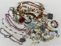 Wide view of entire lot showing necklaces, bracelets, earrings, rings, brooches, pendants and loose stones on white background