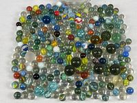 Wide view of many assorted colorful vintage glass marbles spread on white surface